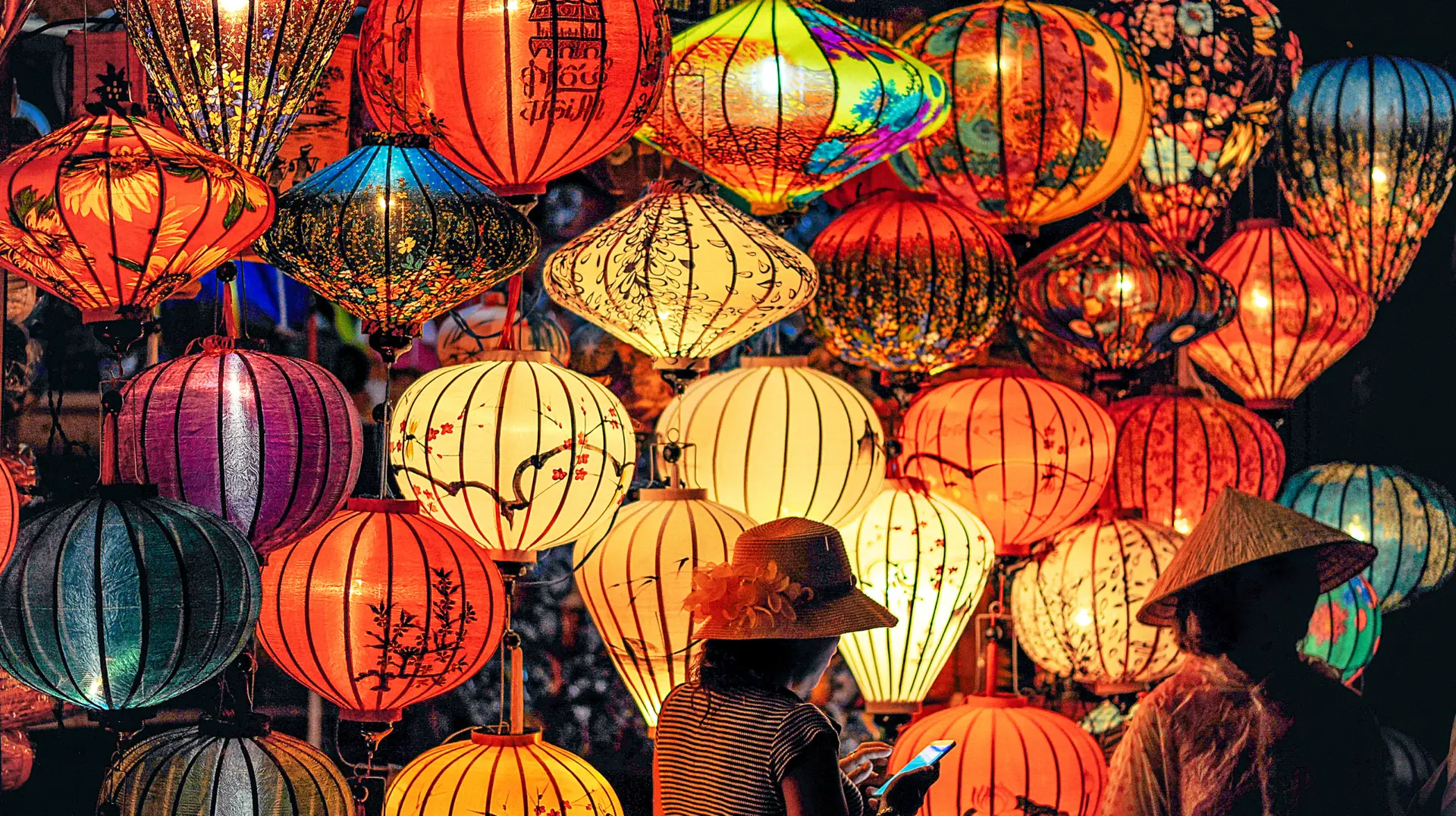 Atmospheric evening street scene in Hoi An Ancient Town, glowing silk lanterns in vivid colors
