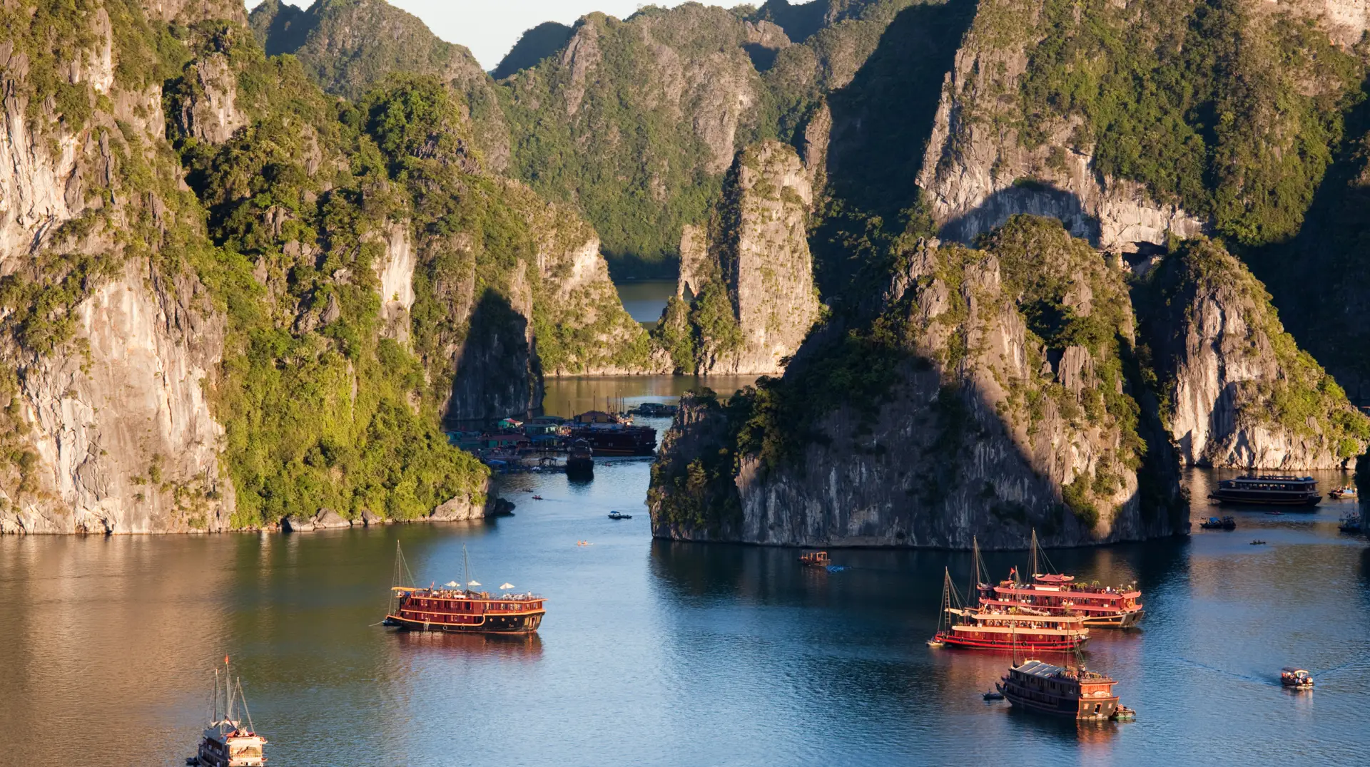 Scene of a luxury wooden junk boat sailing through emerald waters of Halong Bay